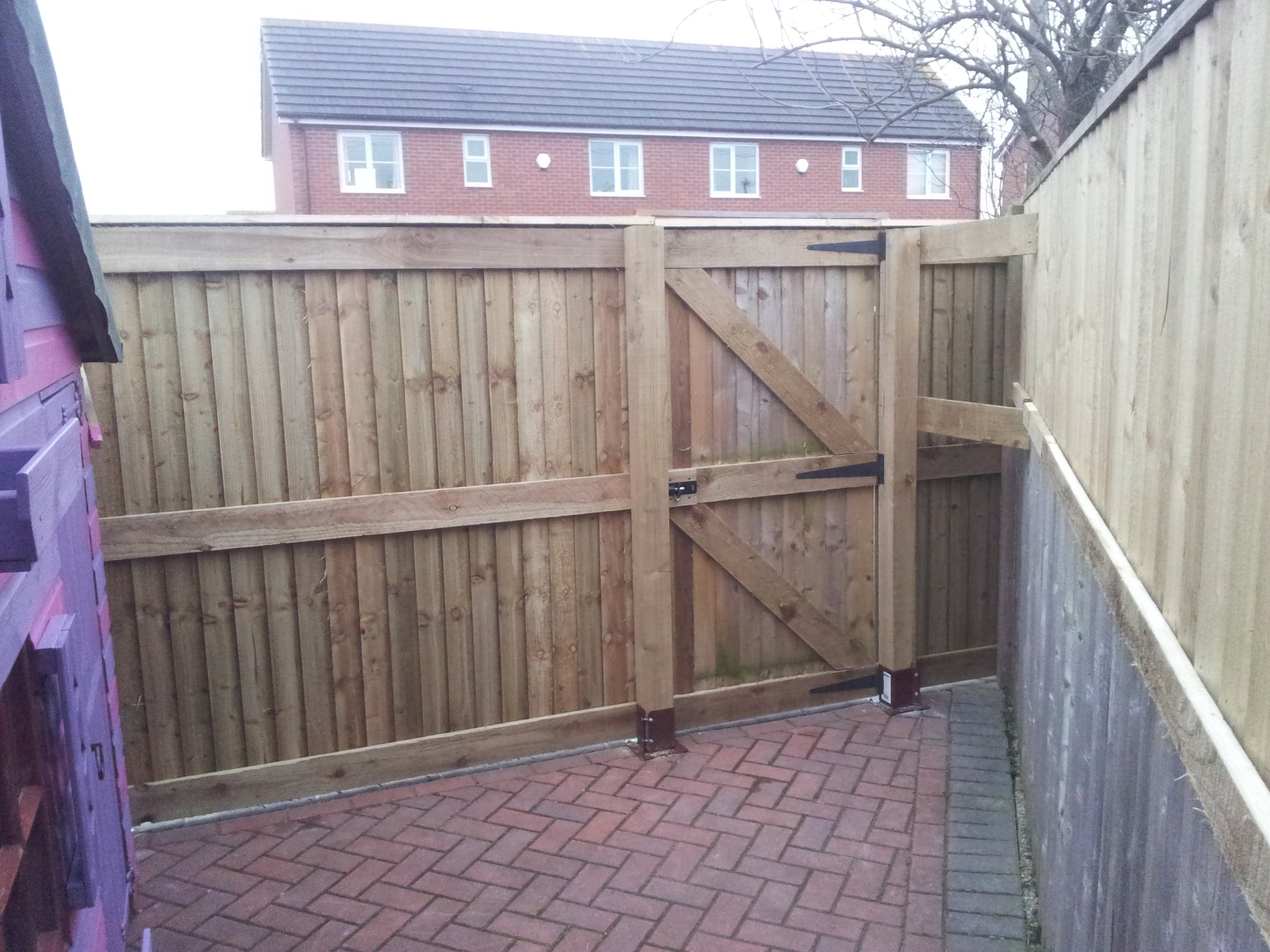 Close-board gate beside a block-paved drive